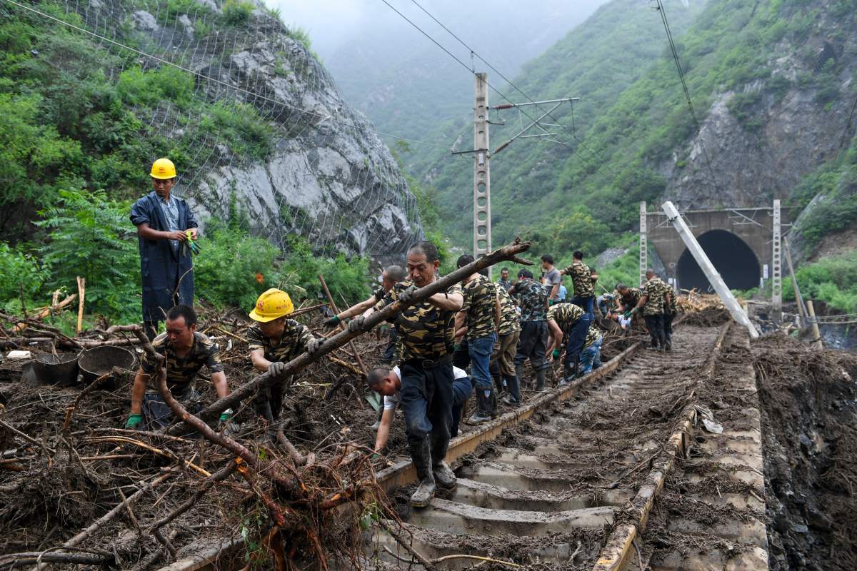 In this photo released by Xinhua News Agency, workers remove fallen debris from a railway track on the outskirts of Beijing on Tuesday, Aug. 1, 2023.