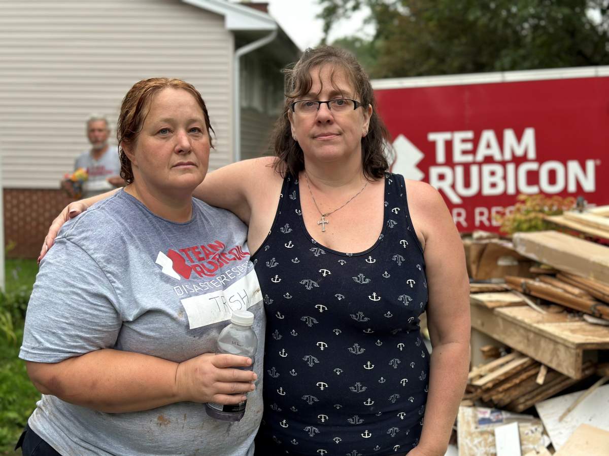 Homeowner Kathryn Peterson stands with a Team Rubicon volunteer who is helping her clean up after the floods.