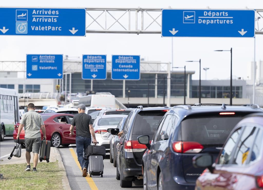 Travellers walk through traffic with their luggage as they try to catch their flights at the Pierre Elliott Trudeau airport, in Montreal, Thursday, Sept. 7, 2023. THE CANADIAN PRESS/Christinne Muschi.