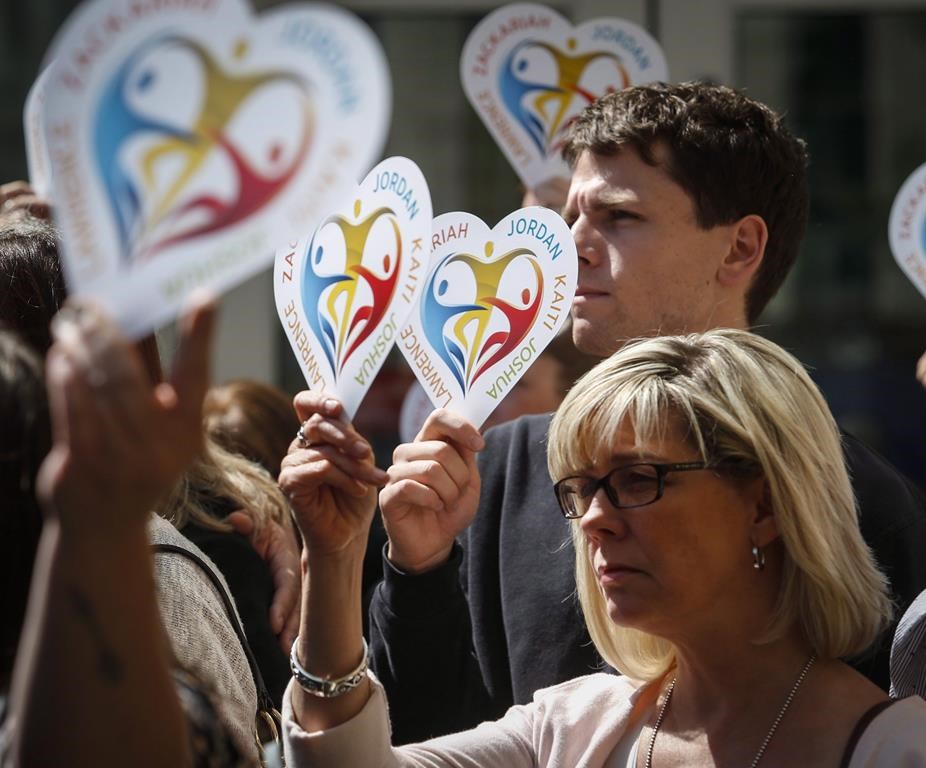 Family members of the five slain students hold heart signs with their names on them following a court decision in Calgary, on Wednesday, May 25, 2016.