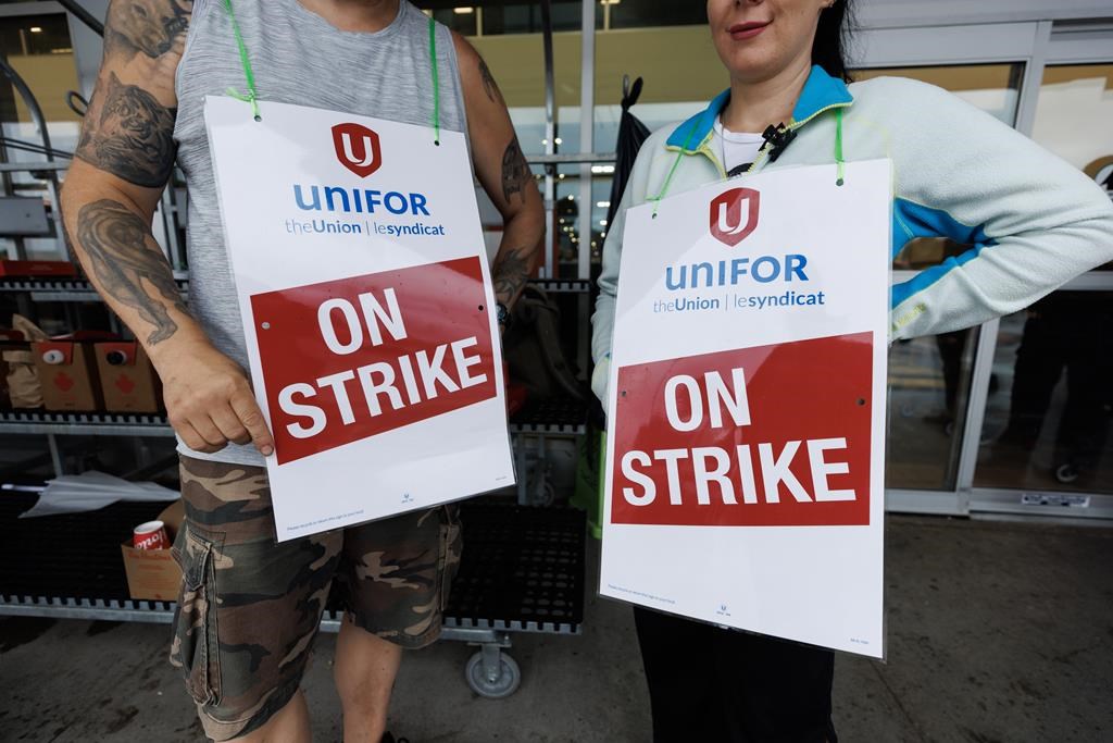Workers hold signs at a picket line outside a Metro grocery store in Toronto as workers rejected a tentative deal triggering a strike of nearly 3,700 grocery store workers in the Greater Toronto Area, Saturday, July 29, 2023. 