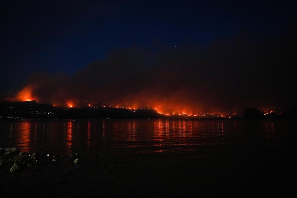 The McDougall Creek wildfire burns on the mountainside above lakefront homes in West Kelowna, B.C., on Friday, August 18, 2023.