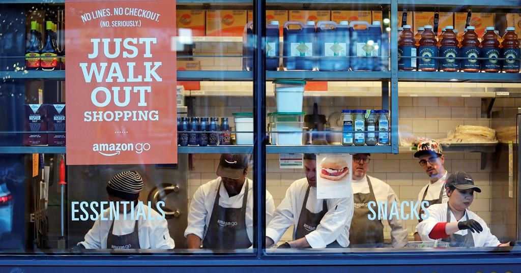 In this Jan. 22, 2018, file photo, workers as seen from a sidewalk window as they assemble sandwiches in an Amazon Go store in Seattle. Toronto and Calgary sports fans will soon be able to skip the lineup when purchasing snacks before or during games. 