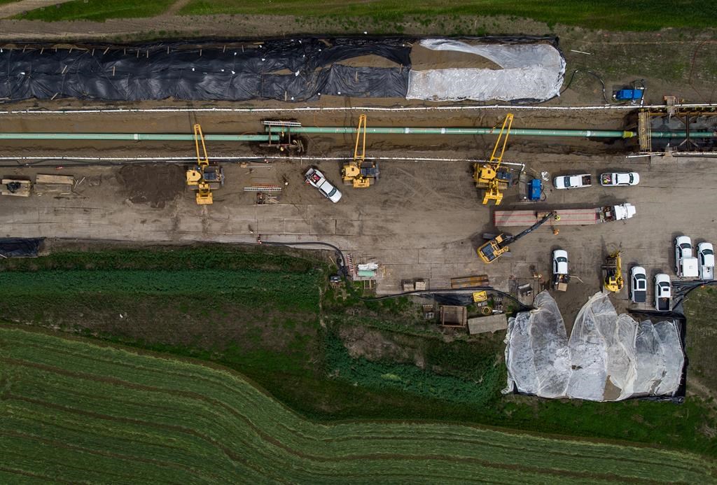 In this photograph taken with a drone, workers lay pipe during construction of the Trans Mountain pipeline expansion on farmland, in Abbotsford, B.C., on Wednesday, May 3, 2023. A B.C. First Nation is asking the Canada Energy Regulator to release its reasons as soon as possible for allowing a modification of the Trans Mountain pipeline's route.