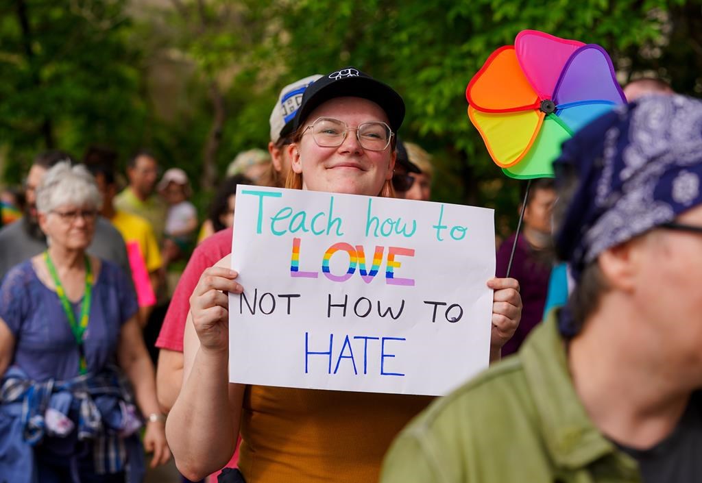A person holds a sign during a pride rally in Saskatoon on Thursday, June 1, 2023. A Saskatchewan judge has granted an injunction over a government policy that requires parental consent when children under 16 want to go by different names and pronouns at school. THE CANADIAN PRESS/Heywood Yu.