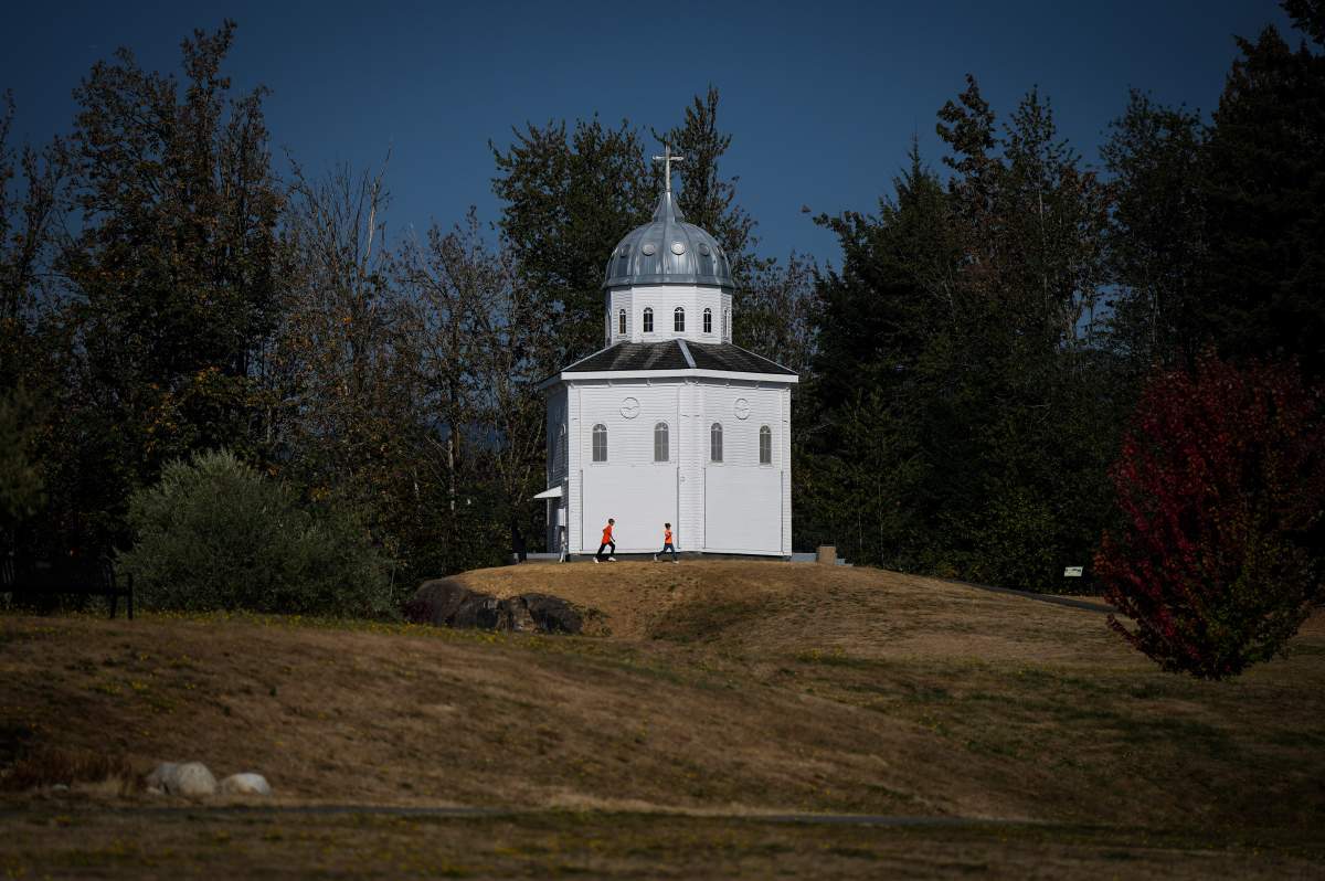 Children wearing orange t-shirts run outside the Grotto that remains at the site of the former St. Mary's Indian Residential School as a ceremony to mark the National Day for Truth and Reconciliation takes place at the bottom of the hill, in Mission, B.C., on Friday, September 30, 2022.
