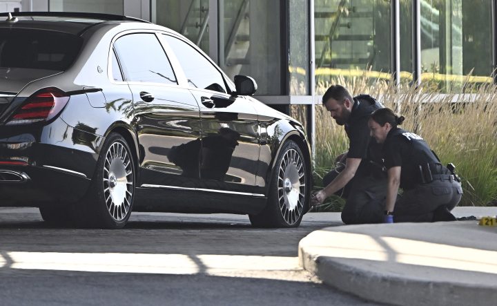 Ottawa Police officers on Sunday examine the front end of a Mercedes Maybach sedan as they collect evidence after a Saturday night shooting at the Infinity Convention Centre that left two dead, in Ottawa.