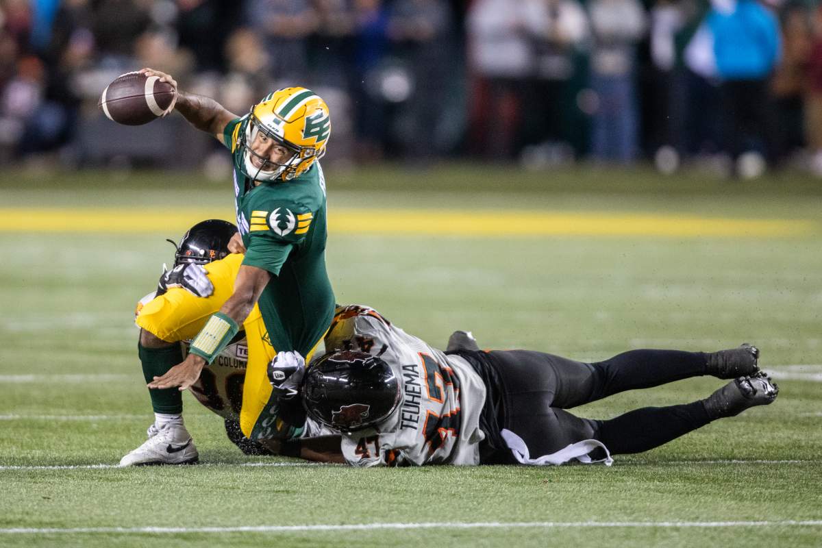 B.C. Lions' Sione Teuhema (47) and Quincy Mauger (36) tackle Edmonton Elks quarterback Tre Ford (2) during second half CFL action in Edmonton on Friday, September 22, 2023.