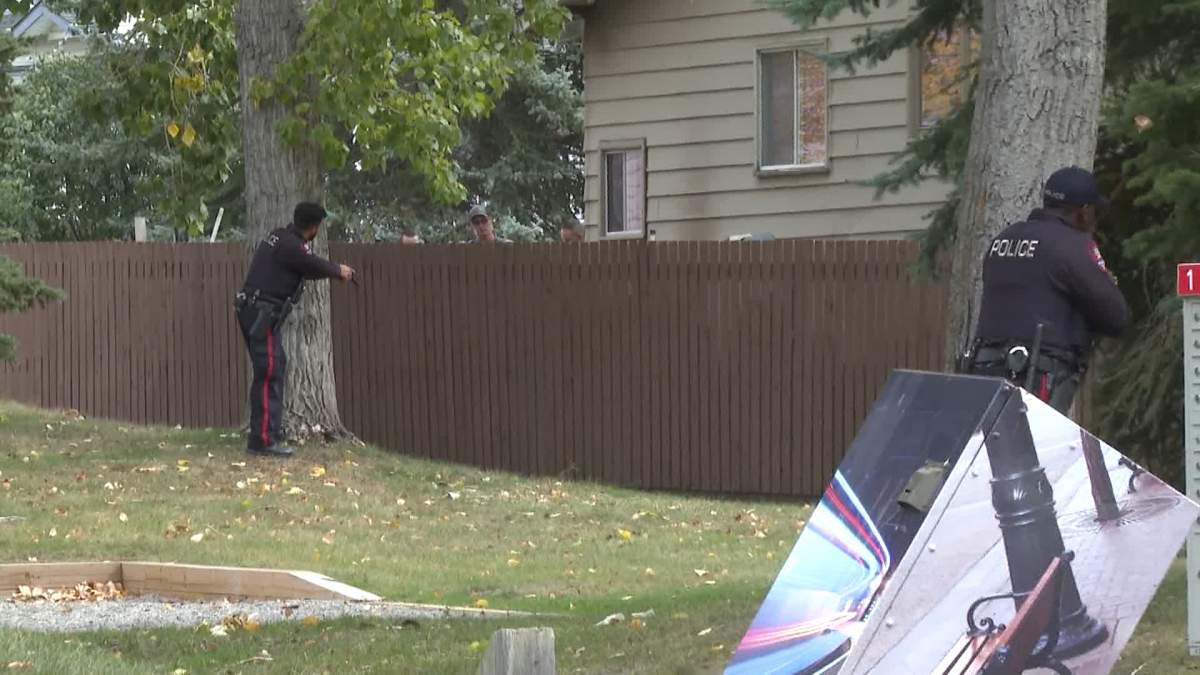 CPS members point their firearms during the arrest of a suspect in an assault and kidnapping suspect in the southeast Calgary neighbourhood of Deer Ridge.