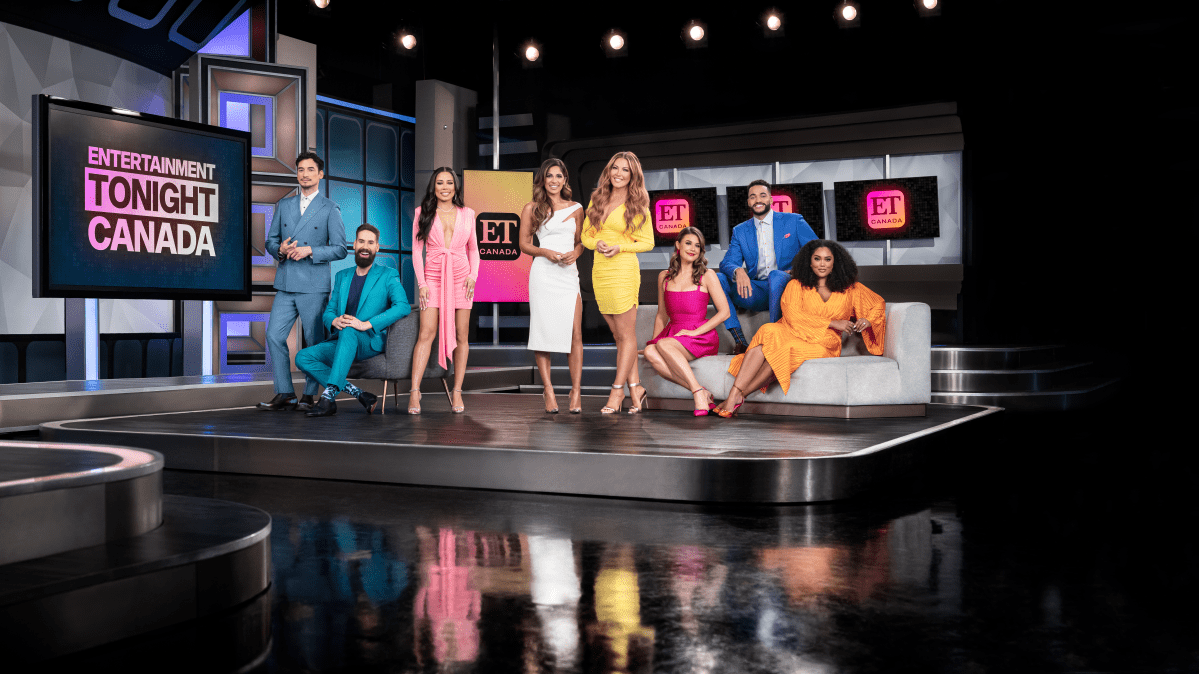 The hosts of Entertainment Tonight Canada stand on set.