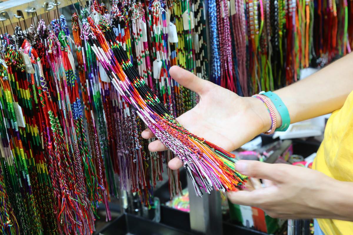 A vendor shows off friendship bracelets in a market stall.