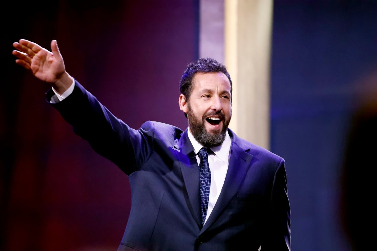 Adam Sandler on stage wearing a suit.