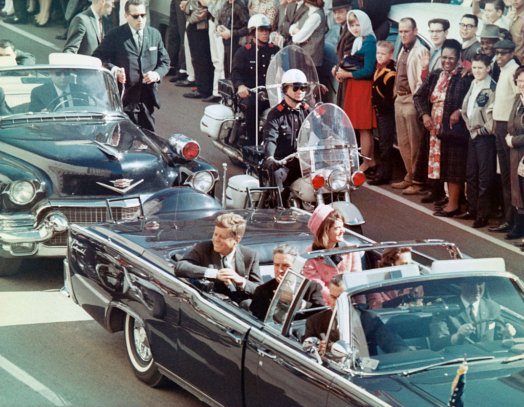 President John F. Kennedy, First Lady Jacqueline Kennedy, Texas Governor John Connally, and others smile at the crowds lining their motorcade route in Dallas, Texas, on November 22, 1963. Minutes later the President was assassinated as his car passed through Dealey Plaza.