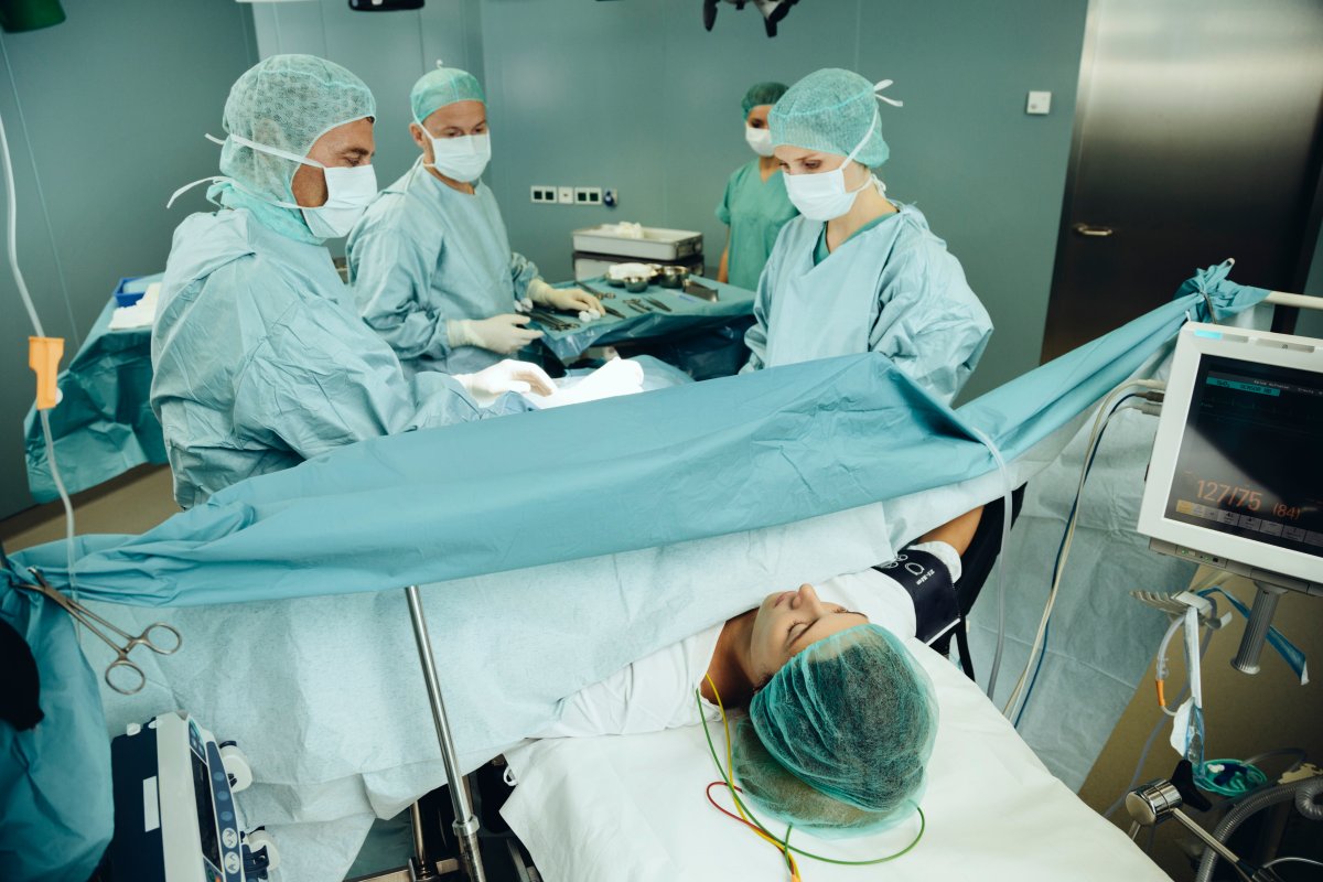 A woman lies on a hospital table, ready for a C-section. She is surrounded by people in scrubs.
