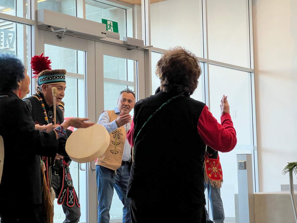 A man sings in front of a totem pole