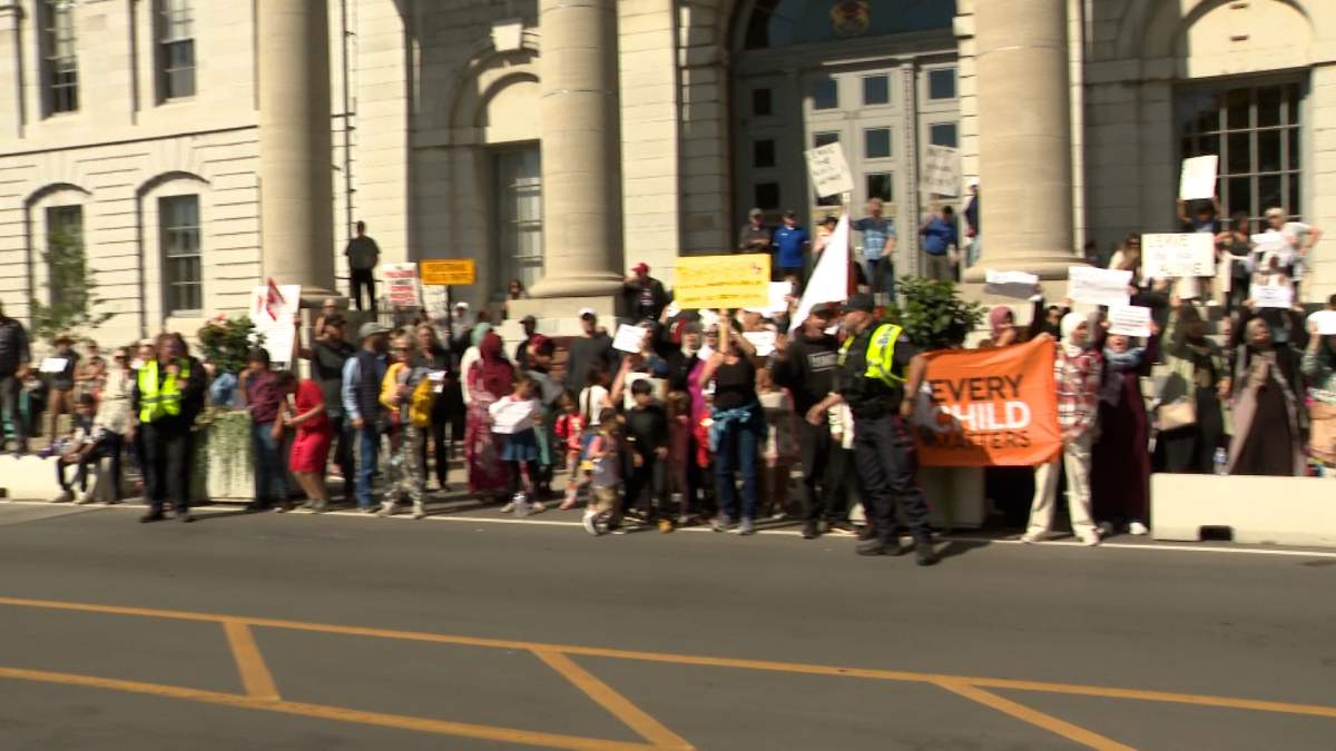 Group of protestors outside a large building in Kingston, Ont.