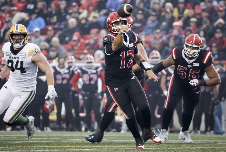 Edmonton Elks defensive lineman Jake Ceresna, left, looks on as Calgary Stampeders quarterback Jake Maier throws the ball during second half CFL football action in Calgary, Alta., Monday, Sept. 4, 2023.