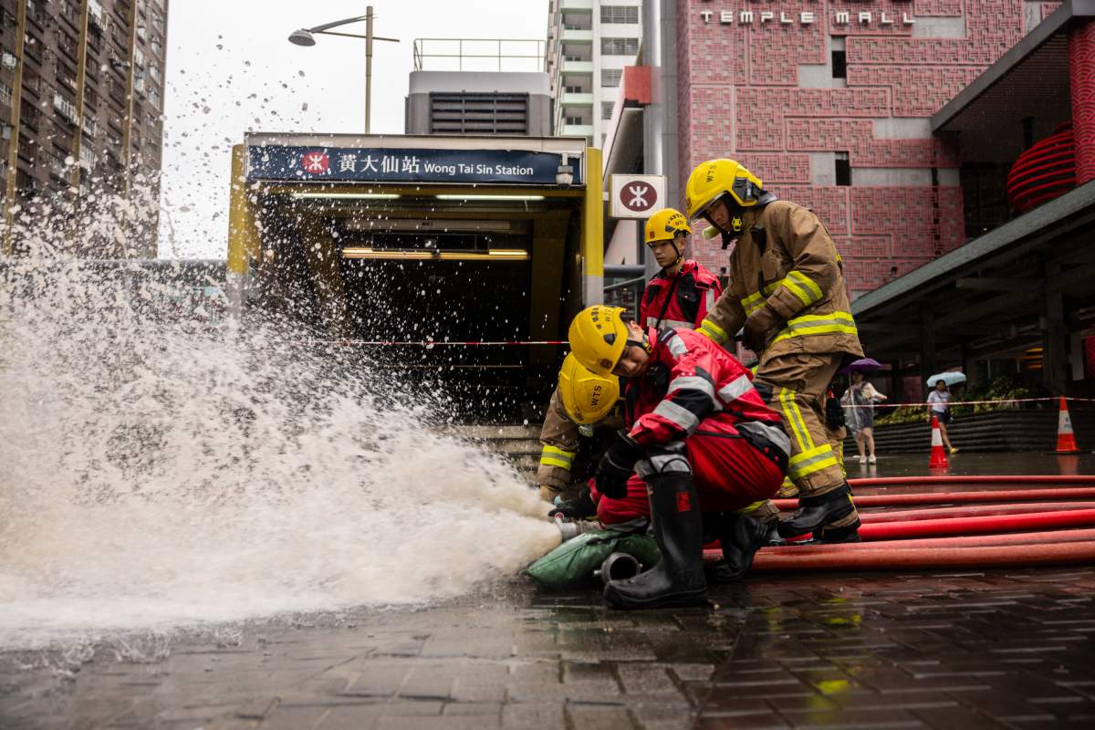 Fire-fighters drain out water outside an MTR station following heavy rainstorms in Hong Kong, Friday, Sept. 8, 2023. (AP Photo/Louise Delmotte)