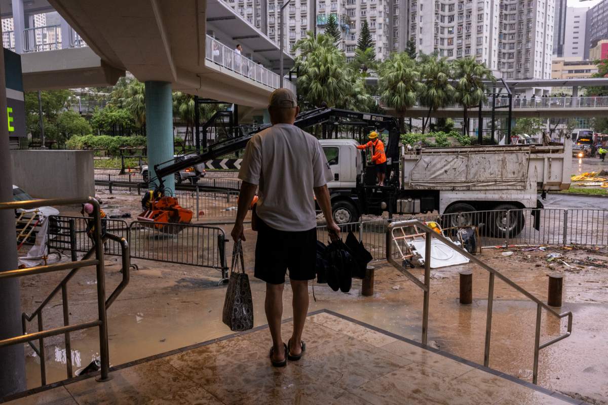 A pedestrian stands near a flooded road following heavy rainstorms in Hong Kong, Friday, Sept. 8, 2023. (AP Photo/Louise Delmotte)
