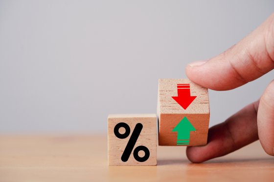 Hand flipping wooden cube block to change between up and down with percentage sign symbol for increase and decrease financial interest rate and business investment growth from dividend concept.