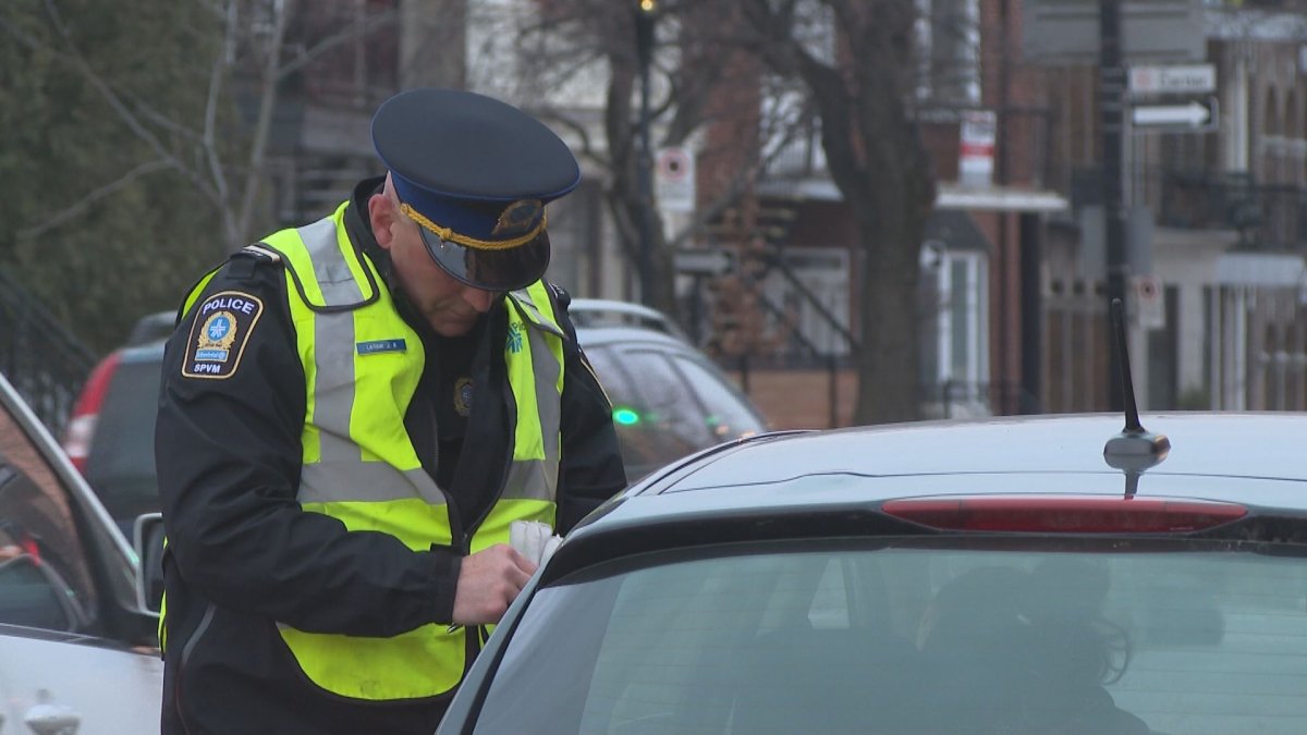 Montreal police officer hands motorist ticket for driving infraction.