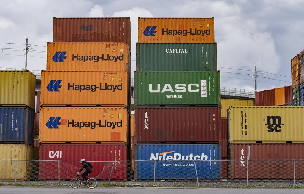 The federal government has announced an investment of up to $150 million to build a new container terminal in Contrecoeur, Quebec, which is about 70 kilometres northeast of Montreal. A cyclist passes shipping containers at a transloading and container storage facility in Montreal, Friday, June 9, 2023. 