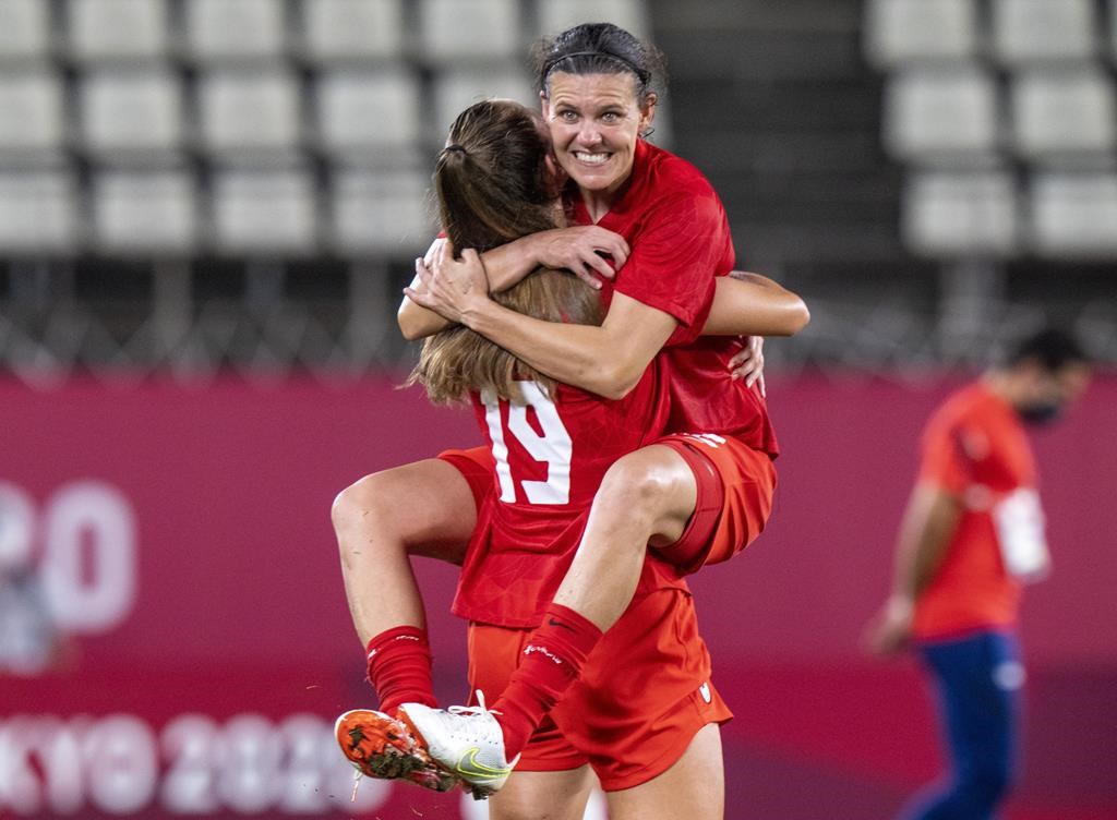 Canada forward Christine Sinclair (12) leaps into the arms of forward Jordyn Huitema (19) to celebrate their win in semifinal football action against the United States of America at the Tokyo Olympics in Kashima, Japan, Monday, Aug. 2, 2020. The star Canadian soccer player has announced her retirement. 