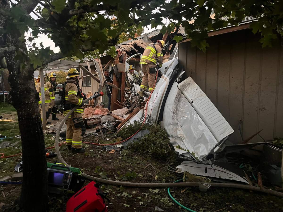 Photo of firefighters searching the wreckage of a plane crash that killed two of the plane's occupants when it plummeted through the roof of a home in Newburg, Oregon.