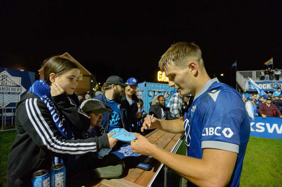 Wanderers centre-back Dan Nimick autographs a young fan’s hat. (Trevor MacMillan/HFX Wanderers FC)
