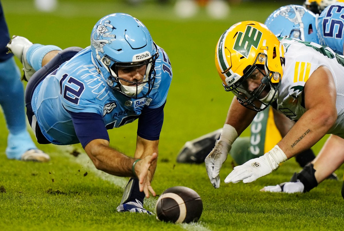 Toronto Argonauts quarterback Chad Kelly (left) and Edmonton Elks defensive lineman Noah Curtis (right) dive for a loose ball during first half CFL football action in Toronto on Friday, October 6, 2023.