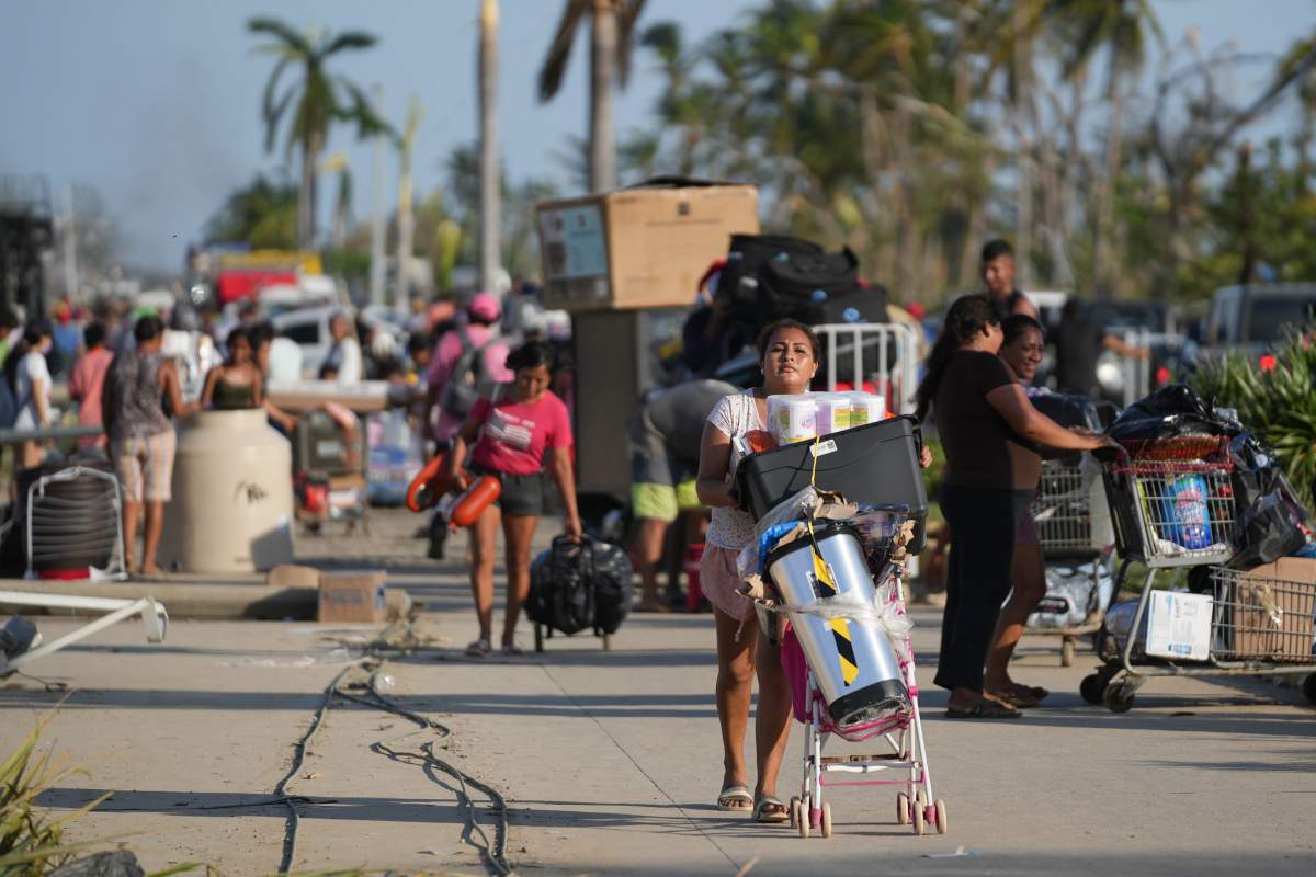 People walk away with items taken from stores after Hurricane Otis ripped through Acapulco, Mexico on Thursday.