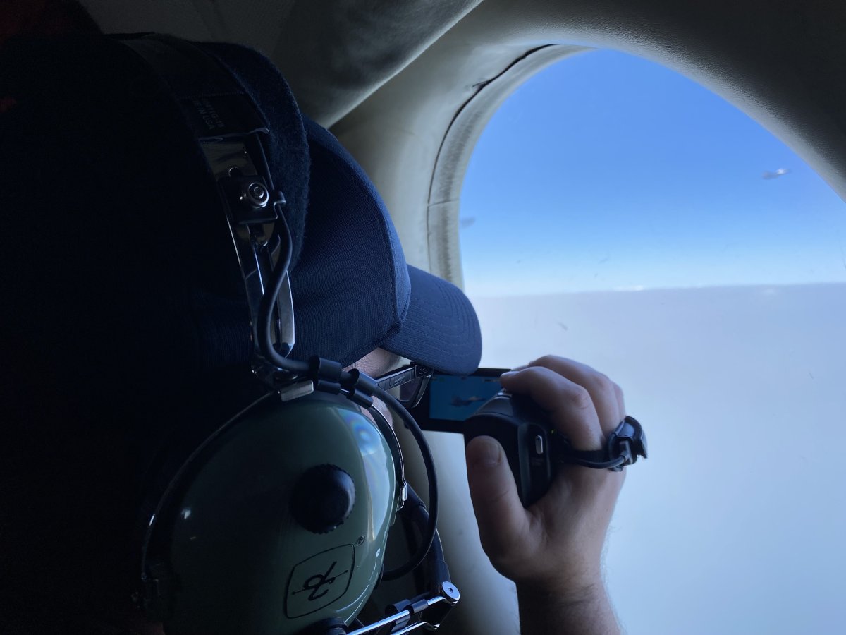 A Chinese fighter jet is seen in the distance out of a Canadian Forces jet window