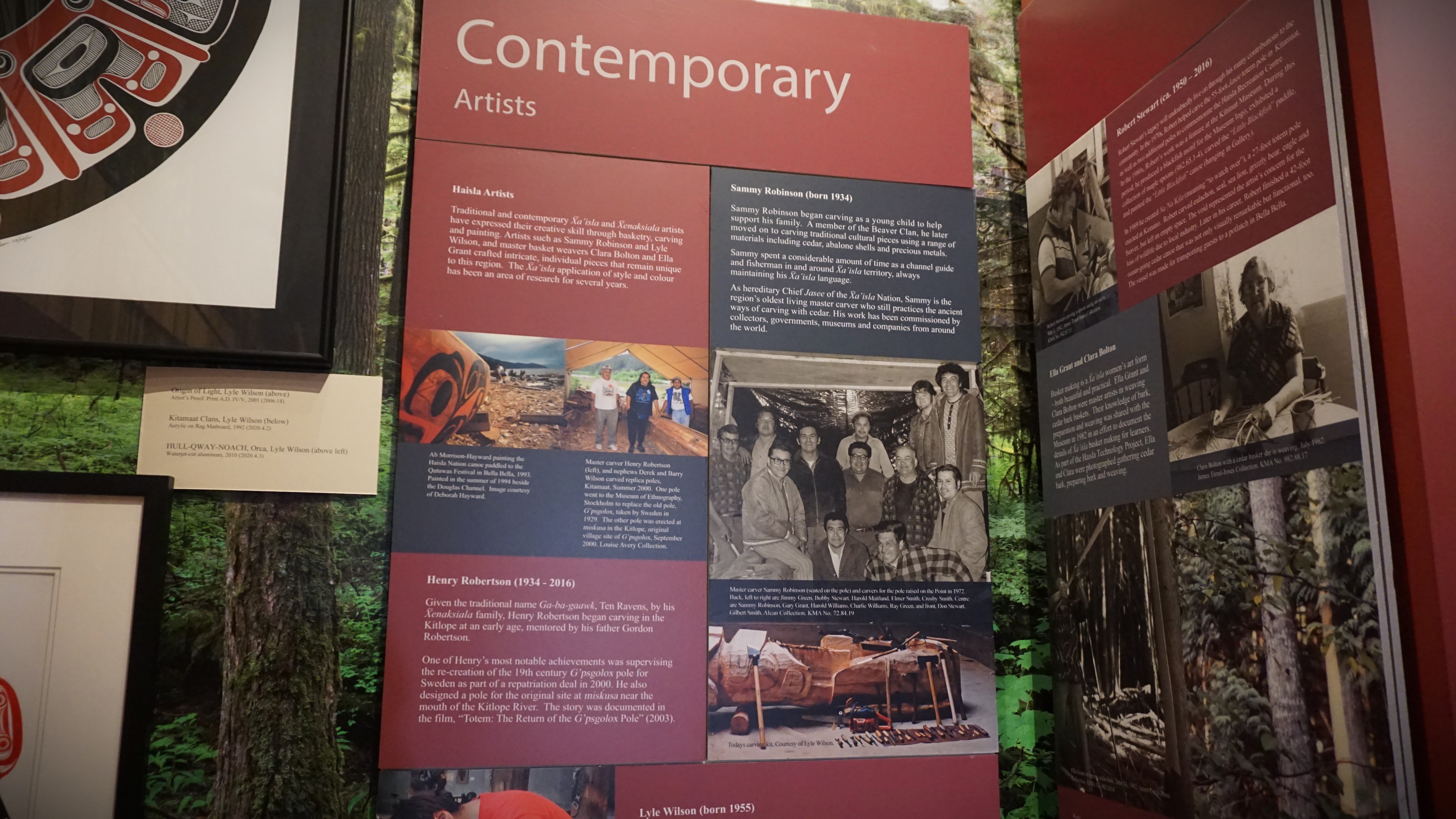 Sammy Robinson is seen sitting on a totem pole, wearing glasses, in a photo of the carvers of a totem pole raised in 1972. The photo is displayed at the Kitimat Museum and Archives.