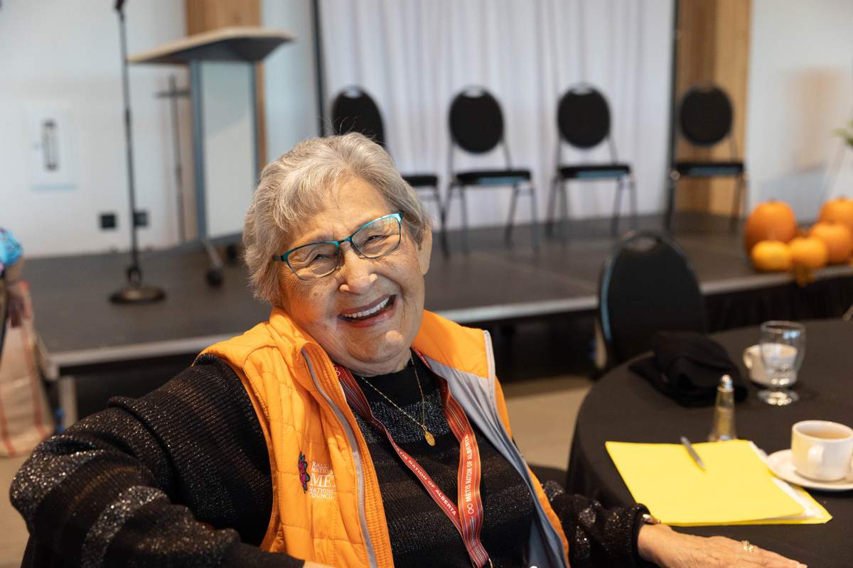 A woman wears an orange vest and smiles at the camera.