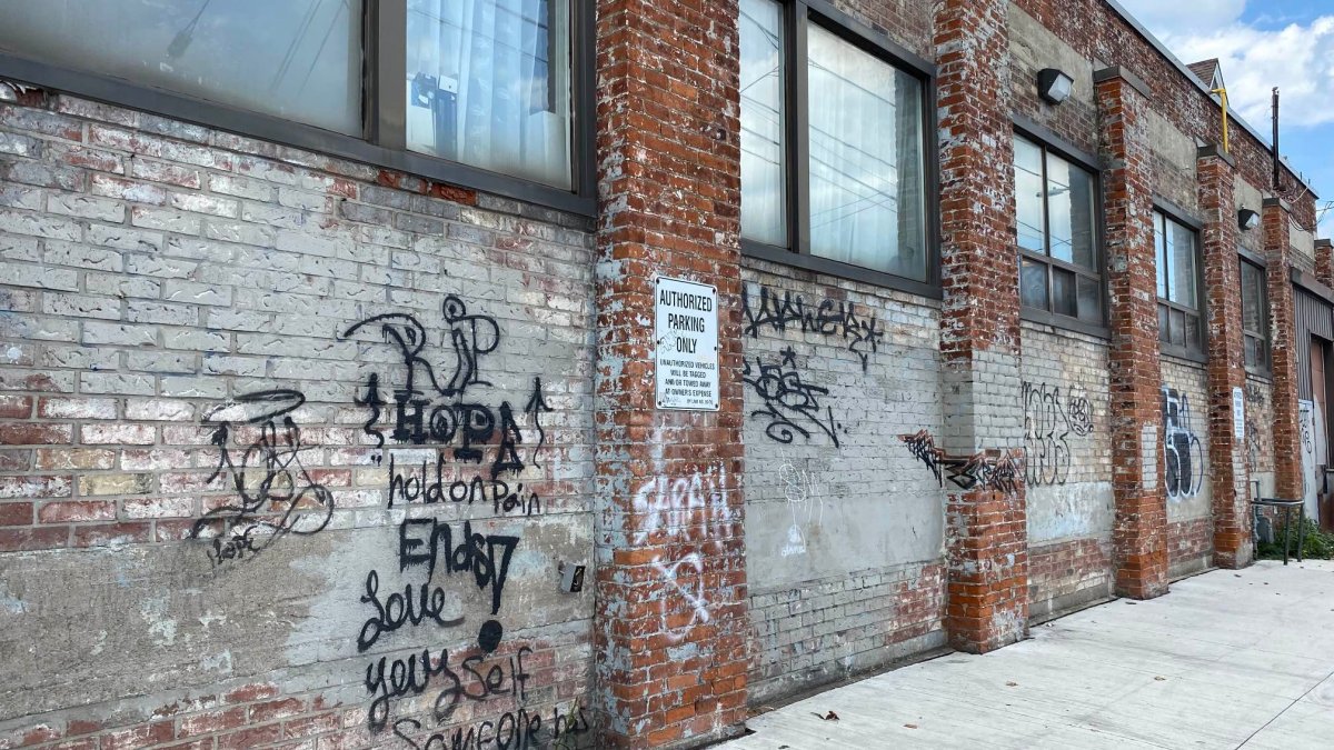 A photo of graffiti on the side of The Hub – a Hamilton non-profit helping the unhoused community. The outlet has until late October to remove the rogue wall art or face fines.
