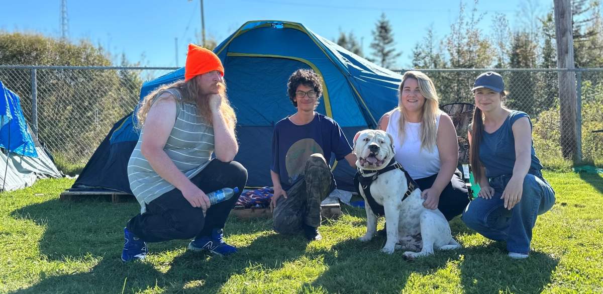 Lower Sackville Ballfield residents, including Jacob Hicks (left), speak with community volunteers Samantha Banks and Michelle Calder on Oct. 12, 2023. They’re joined by one of the dogs who lives on site — “Cheeseburger.”