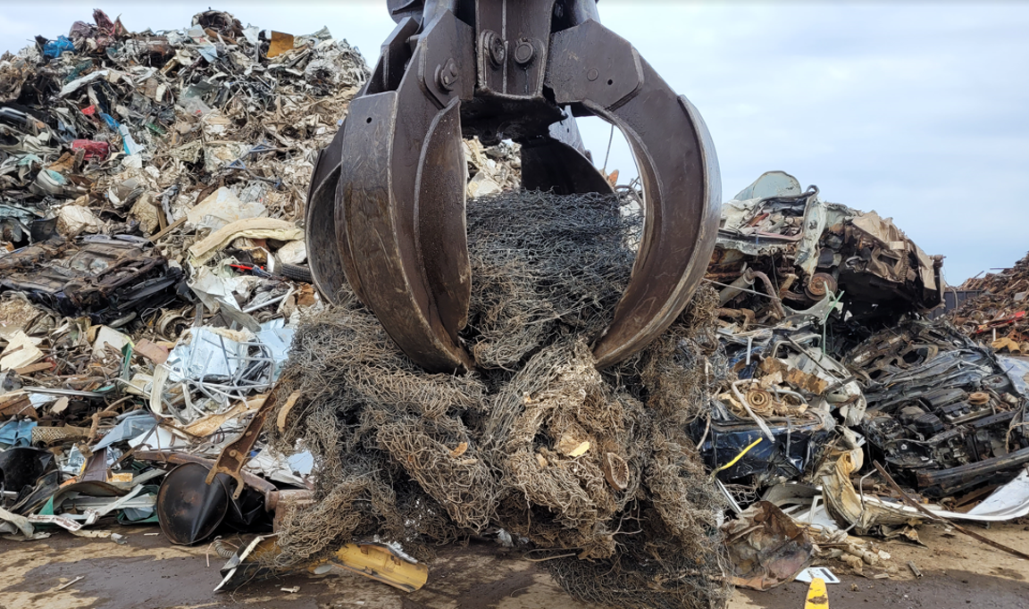 Operators use a bundled piece of chain link fence to sweep the trailer of dirt and remaining debris.