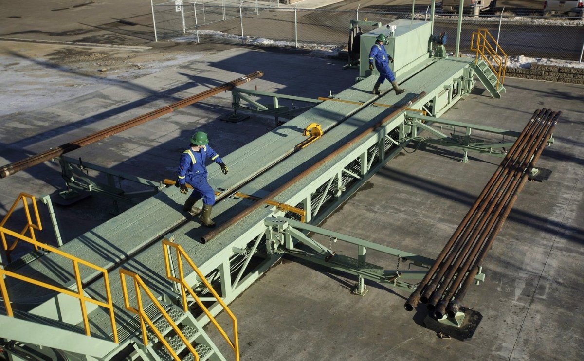 Trainees roll pipe off a catwalk during a training session to lay down drill pipe on a rig floor at Precision Drilling in Nisku, Alta., on Friday, January 20, 2016. 