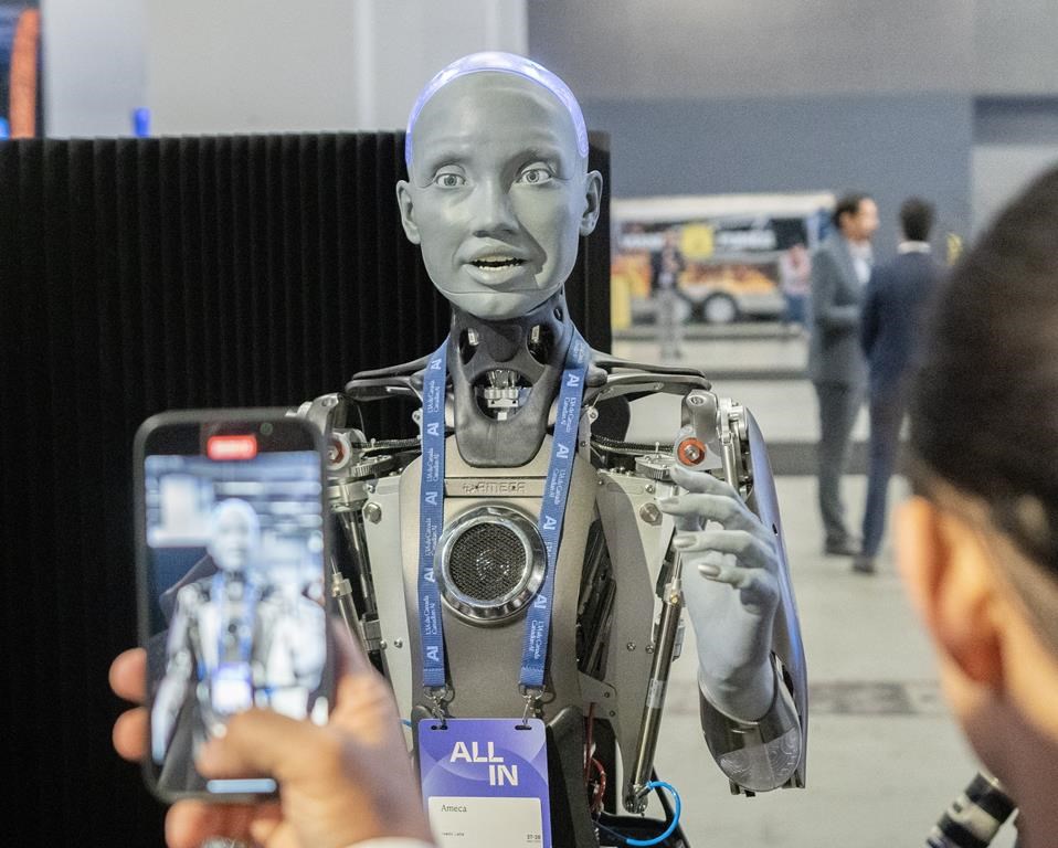 People take photos of an AI robot at the All In Artificial Intelligence conference on Sept. 27 in Montreal.