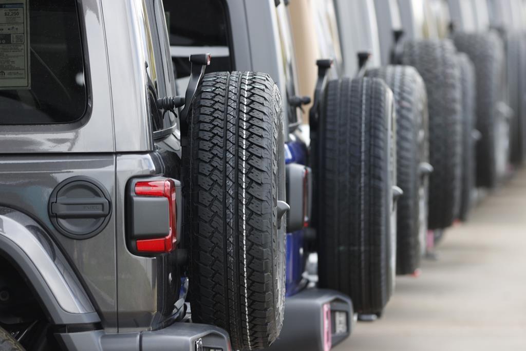 FILE - Spare tires are seen on a long row of unsold 2020 Jeep Wranglers.(AP Photo/David Zalubowski, File).