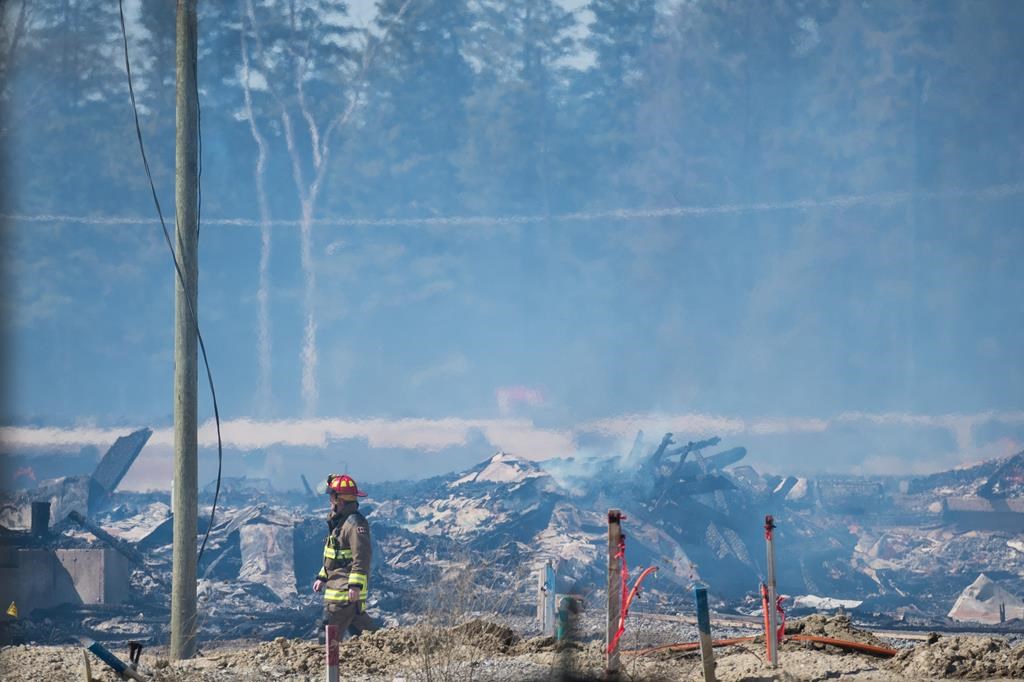Ontario is planning on boosting benefits for injured workers and improving cancer coverage for firefighters under legislation set to be introduced soon. A firefighter walks through the damage as they continue to battle a large fire in Vaughan, Ont., Wednesday, April 12, 2023. 