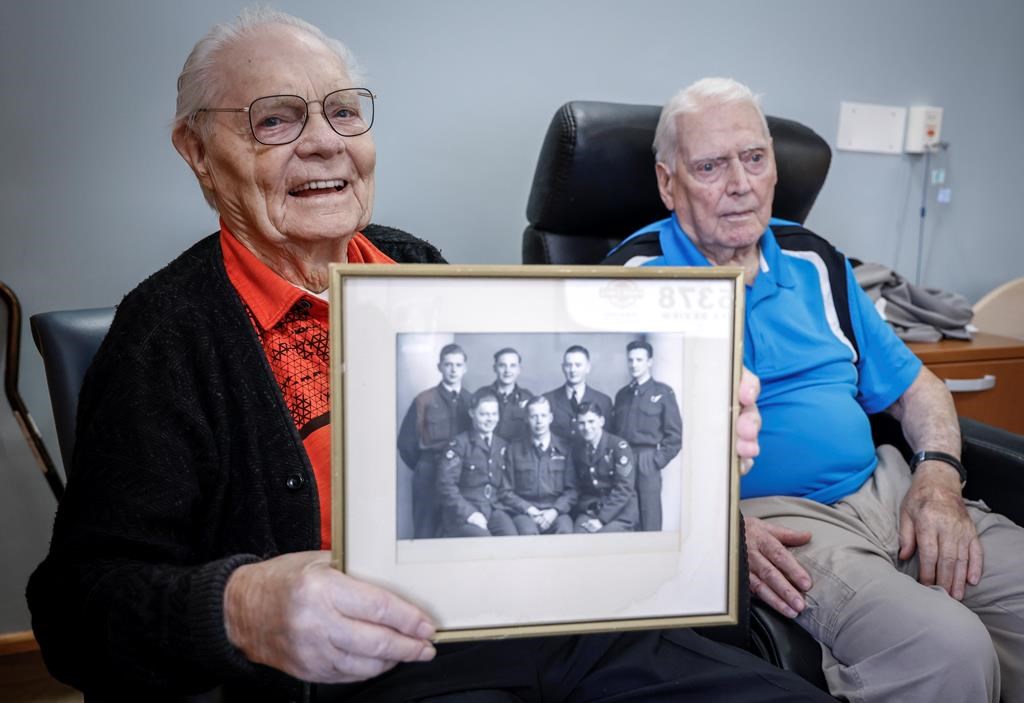 Royal Canadian Air Force veteran Bill Cook, left, holds a Second World War photo of his Halifax bomber crew members, as fellow veteran Hank Jackman, 103, looks on in Calgary, Tuesday, Nov. 7, 2023. Both were Halifax bomber tail gunners during the Second World War. THE CANADIAN PRESS/Jeff McIntosh