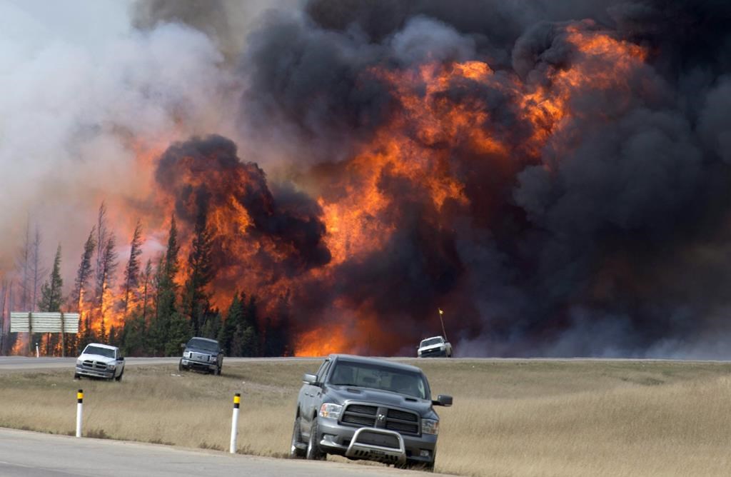 FILE - A wildfire burns south of Fort McMurray, Alberta, near Highway 63 on Saturday, May 7, 2016.