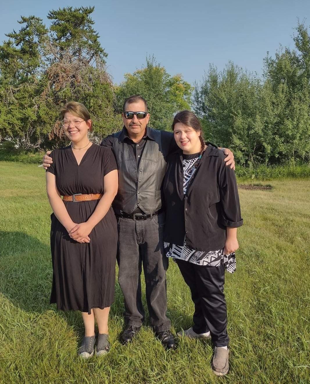 A group of three people stand together