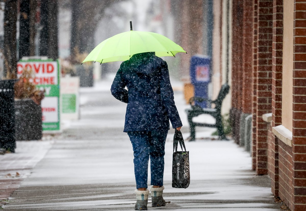 A pedestrian walks as snow falls.