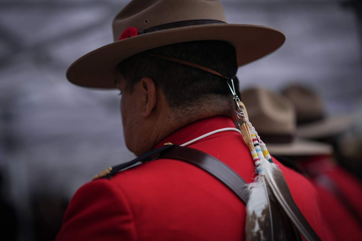 An RCMP officer is pictured from behind with an eagle feather attached to his stetson