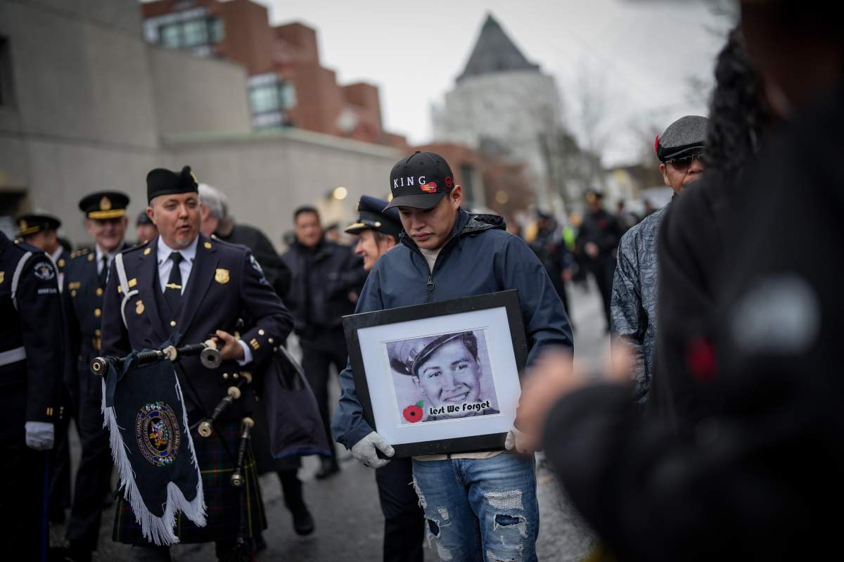 A man carries an archive portrait of a young soldier.