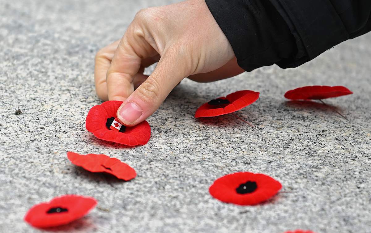 A person places a poppy on the cenotaph following a Remembrance Day ceremony in Montreal, Saturday, November 11, 2023.