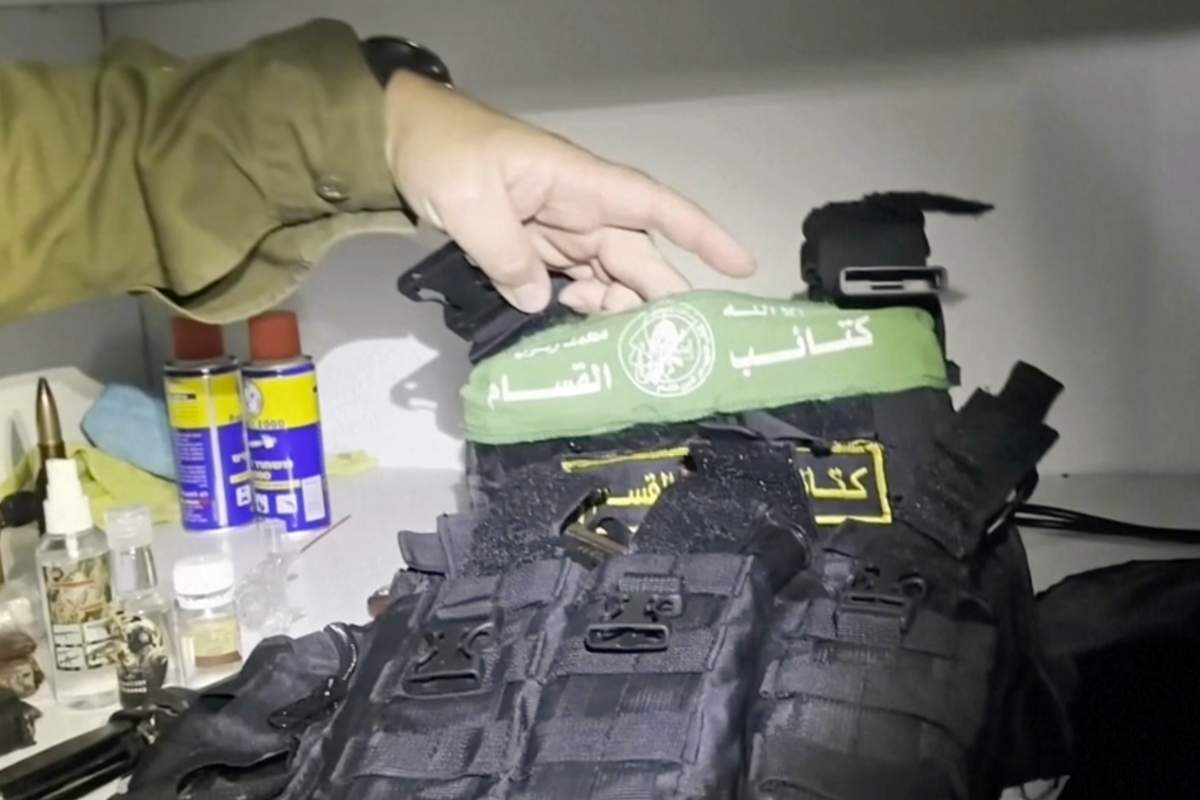 In this image taken from a video released by the Israeli Defense Forces, Wednesday, Nov. 15, 2023, Lt. Col. Jonathan Conricus, an Israeli military spokesman, holds up a bullet proof vest with a Hamas insignia that was found along with weapons the IDF says were found in a medical closet at the MRI center at Al-Shifa hospital in Gaza City.