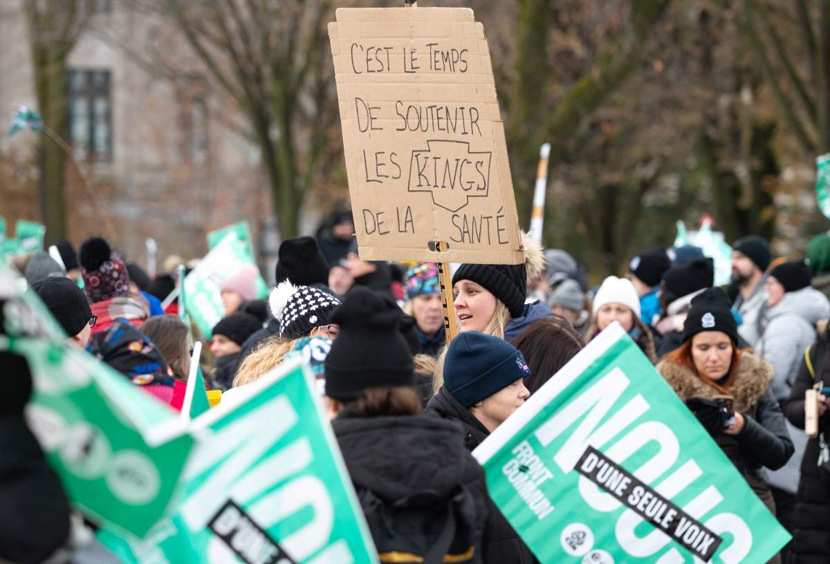 A woman holding a sign saying they are the Kings of health during a demonstration at the National Assembly, Thursday, Nov. 23, 2023 in Quebec City. Adding to the tension is a recent decision by the Quebec government to spend millions of taxpayer dollars to bring the Los Angeles Kings NHL team to Quebec City next year for two pre-season games.